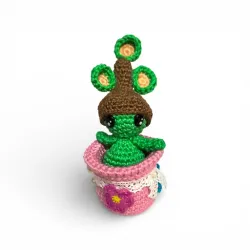 Petite figurine verte en crochet, en forme de plante, dans son pot