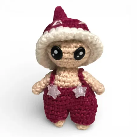 Petite figurine champignon Bolet en crochet bordeaux avec salopette et étoiles.