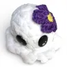 Mini pieuvre blanche en fil chenille avec jolie fleur violette crochetée, vue de dessus.
