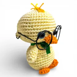 Vue de côté du poussin artisanal jaune avec petites lunettes rondes, décoration de Pâques.