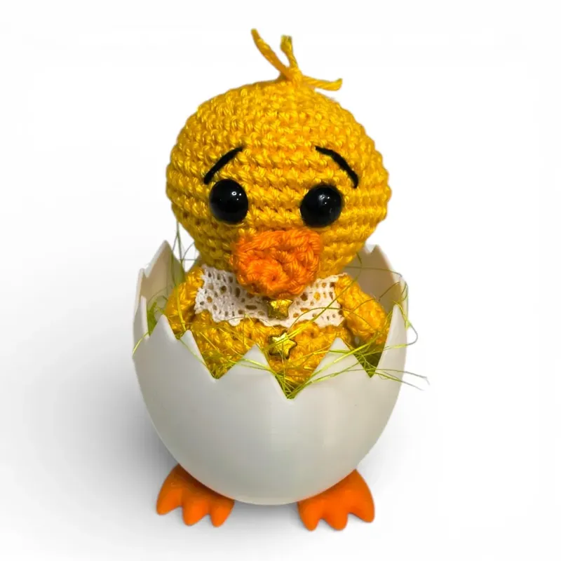 Petit poussin amigurumi avec collerette en dentelle blanche et broderies étoiles dorées.