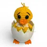 Petit poussin amigurumi avec collerette en dentelle blanche et broderies étoiles dorées.